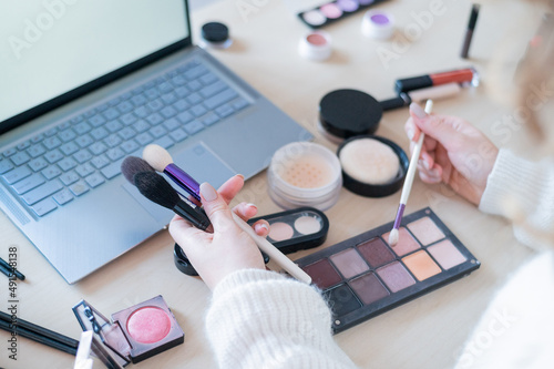 Foto A faceless woman watches online training from a professional makeup artist on a laptop
