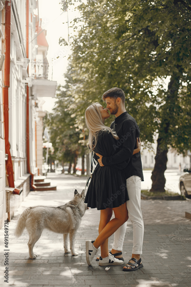 Young stylish couple walking with dog in street Young stylish couple walking with dog in street