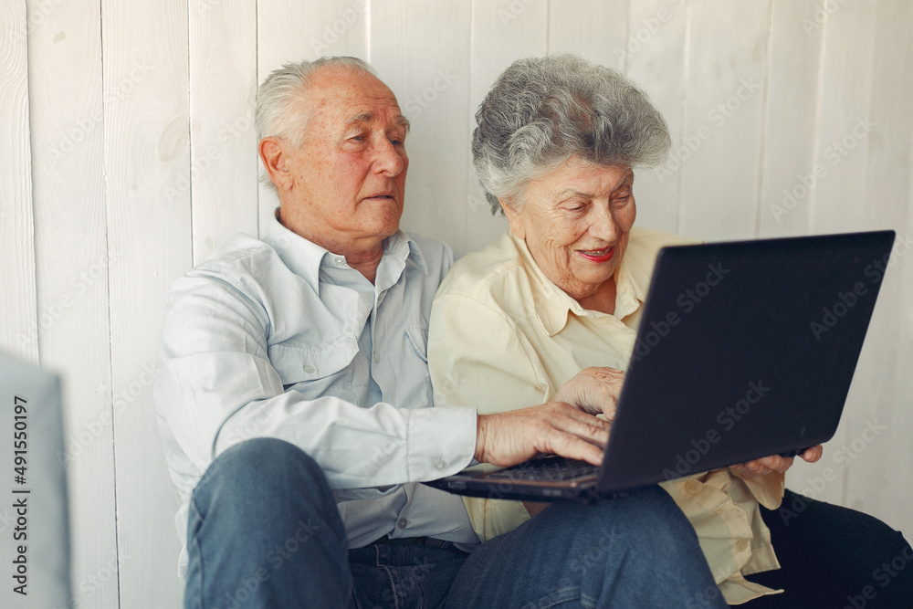 Elegant old couple sitting at home and using a laptop