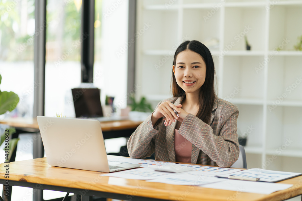 Charming asian businesswoman sitting working on laptop in office. Charming asian businesswoman sitting working on laptop in office.
