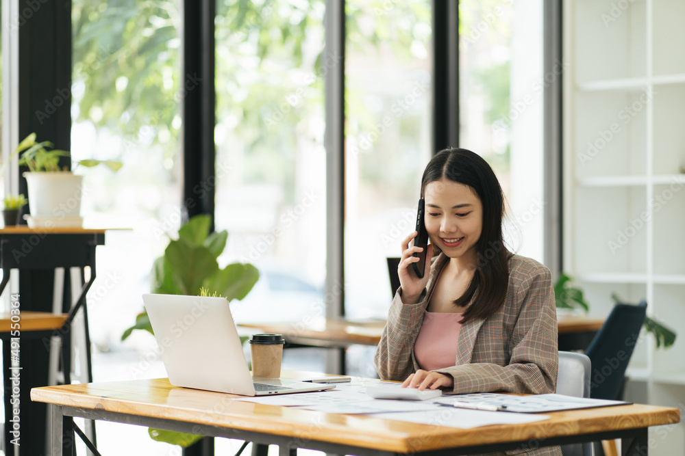Asian businesswoman talking on the phone using laptop at the office. Asian businesswoman talking on the phone using laptop at the office.