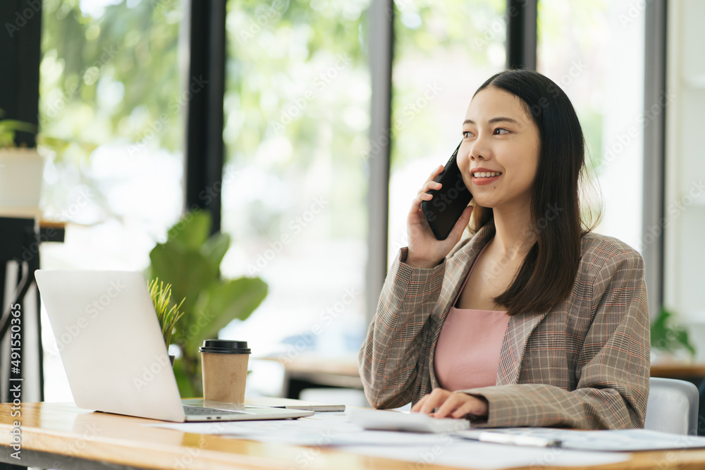 Asian businesswoman talking on the phone using laptop at the office. Asian businesswoman talking on the phone using laptop at the office.