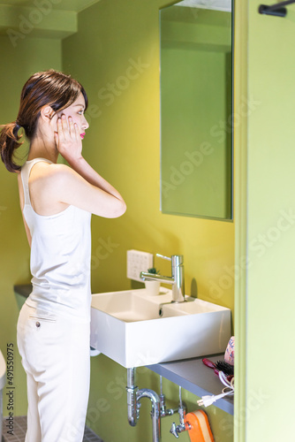 洗面台で顔を洗う若い女性