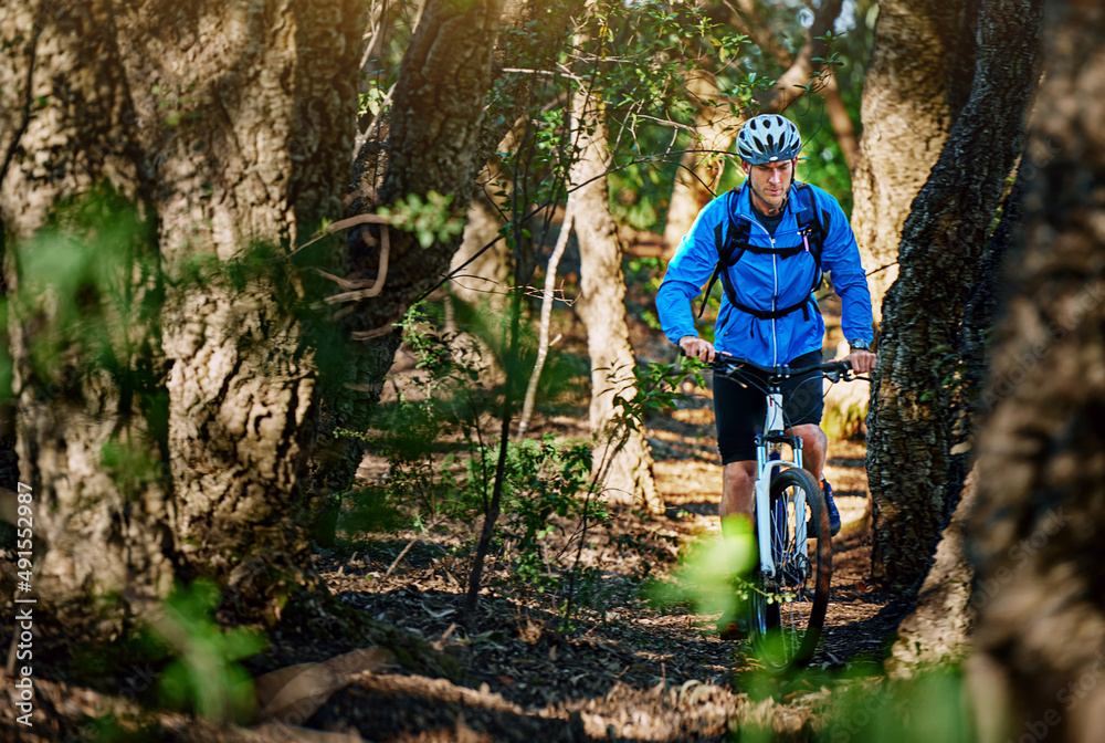 Obraz premium Forest fitness fanatic. Shot of a male cyclist riding along a mountain bike trail.