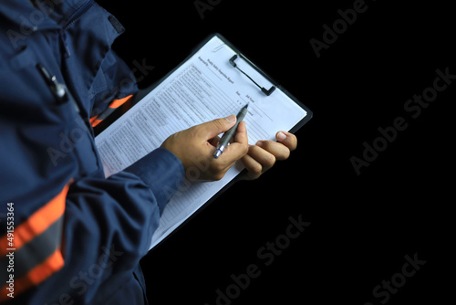 Photo An auditor or inspector holds a clipboard and checklist of assessments and inspections on a black background