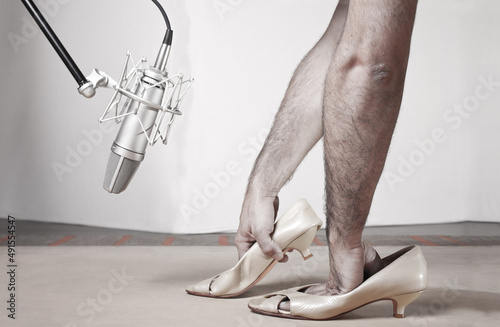 Foley woman steps with caucassian man hands inside femail shoes front a silver studio mic over a wood table