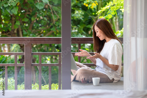 Free Download Portrait image of a young woman using laptop computer for video call and working online at home - GFXLoad