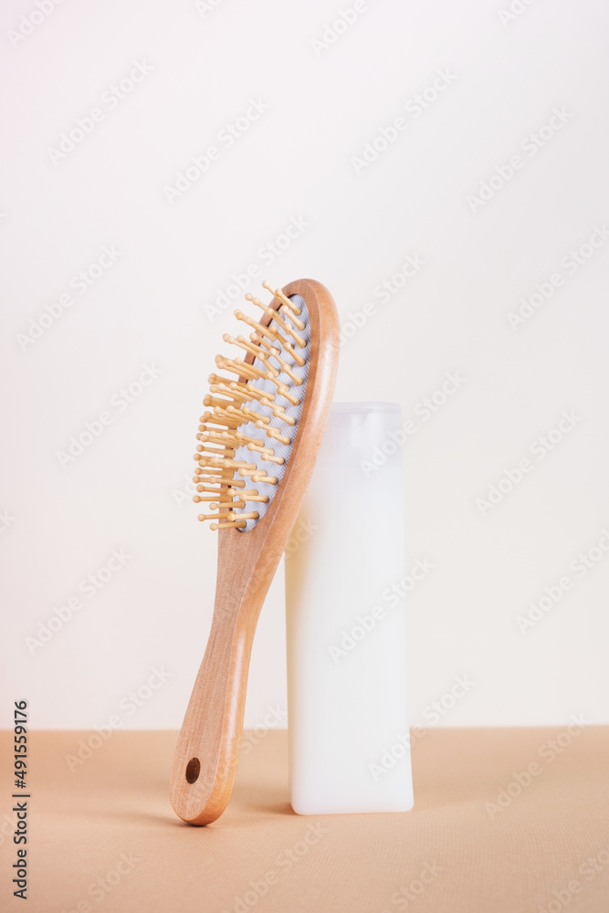 Still life with shampoo bottle and hair brush on beige background. Hair care concept, natural cosmetics. Vertical, minimal composition Still life with shampoo bottle and hair brush on beige background. Hair care concept, natural cosmetics. Vertical, minimal composition