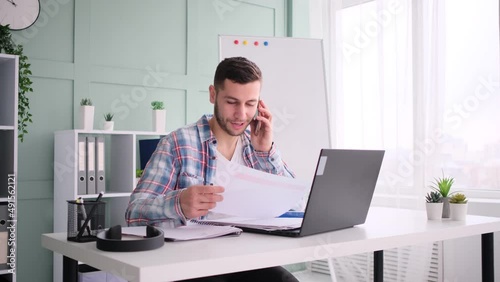 Young entrepreneur working on laptop and talking on mobile phone