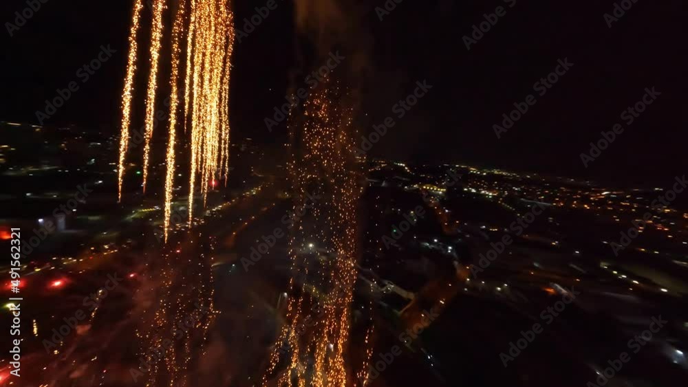 Dynamic drone flight through beautiful pyrotechnics during firework explosion at night 