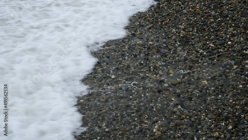 Close up of ocean waves flowing over rocky beach.