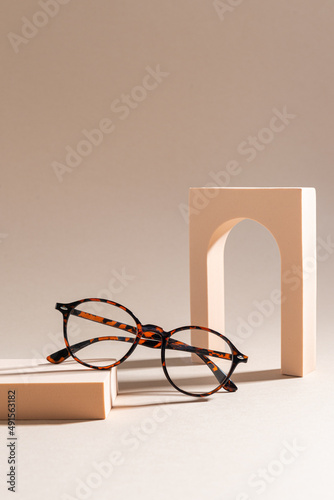 Trendy glasses in plastic frame on beige background. Glasses sale poster. Optic store sale-out offer. Copy space. Optic store discount. Eyewear fasion promotion. Eyeglass Tortoiseshell frame. Vertical photo