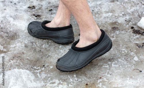 Men's feet in galoshes on the snow. Close-up