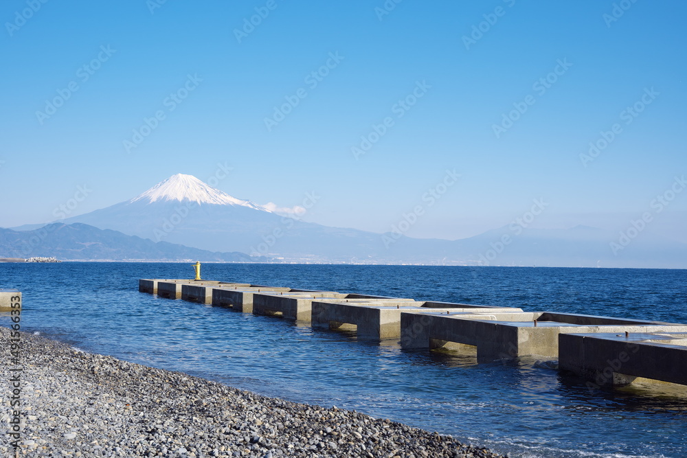 晴天の日の遠くに見える雪の富士山と砂浜から見える美しい景色