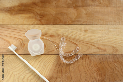 Toothbrush, mouthpiece and dental floss on a wooden table photo