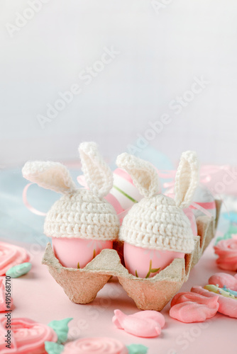 Happy Easter holiday concept with cute handmade eggs, knitted bunny hats and sweet pink decor, copy space. Greeting card, banner for your site, flyer, banner, invitation, discount card