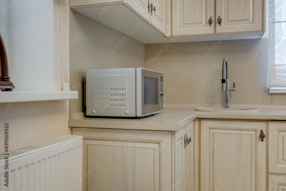 Fototapeta premium Interior of the small living equipped kitchen in studio apartments in minimalistic style with light color