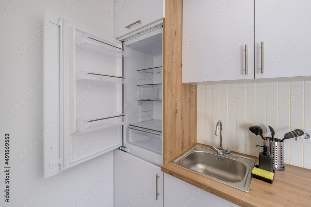 Interior of the small living equipped kitchen in studio apartments in minimalistic style with light color Interior of the small living equipped kitchen in studio apartments in minimalistic style with light color
