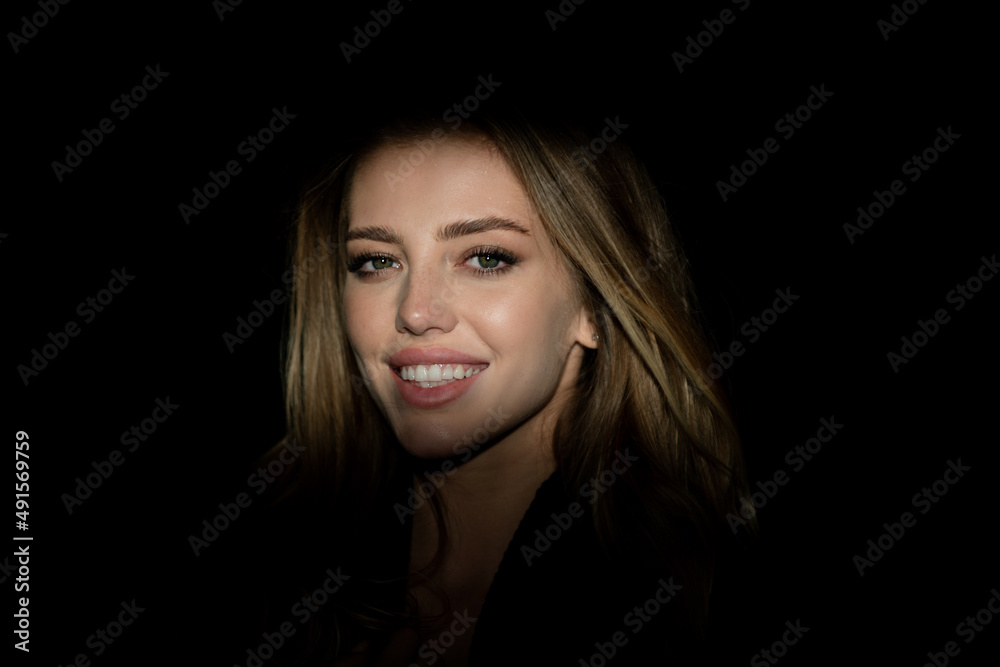 Beauty close up face of beautiful pretty girl on black. Portrait of elegant woman with light on a black background. Beautiful female face in the darkness. Sensual smile, smiley face. Beauty close up face of beautiful pretty girl on black. Portrait of elegant woman with light on a black background. Beautiful female face in the darkness. Sensual smile, smiley face.
