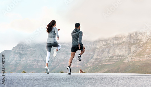 Stretching helps improve range of motion and loosen up muscles. Rearview shot of a sporty young man and woman exercising together outdoors. photo