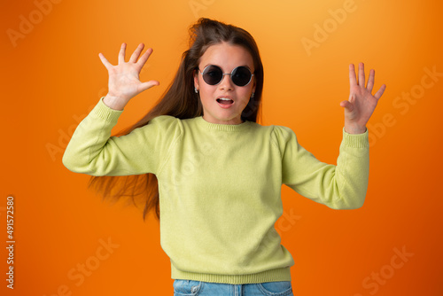 Funny caucasian teen girl in eyeglasses isolated on orange background © fotofabrika