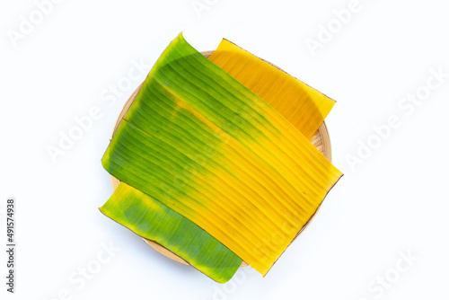 Yellow green banana leaves in bamboo weave plate on white background.