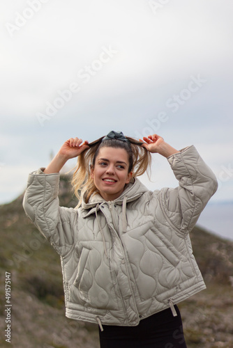  Pretty young woman is tidying her hair at outside. Ponytail hair. She is so happy and smiling. Vertical photo.