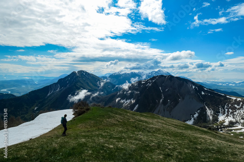 Active woman hiking on Frauenkogel with scenic view on mountain peaks in the Karawanks, Carinthia, Austria. Border with Slovenia. Triglav National Park. Kahlkogel (Golica). Snow melting in spring