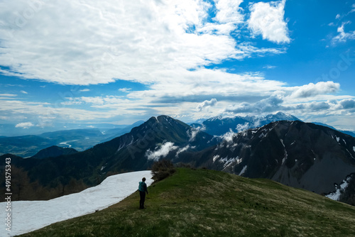 Active woman hiking on Frauenkogel with scenic view on mountain peaks in the Karawanks, Carinthia, Austria. Border with Slovenia. Triglav National Park. Kahlkogel (Golica). Snow melting in spring