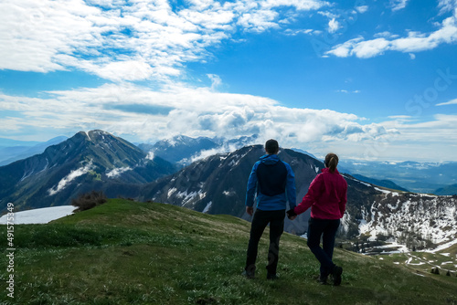 Active couple hiking on Frauenkogel with scenic view on mountain peaks in the Karawanks, Carinthia, Austria. Border with Slovenia. Triglav National Park. Kahlkogel (Golica). Snow melting in spring © Chris