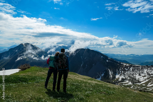 Active couple hiking on Frauenkogel with scenic view on mountain peaks in the Karawanks, Carinthia, Austria. Border with Slovenia. Triglav National Park. Kahlkogel (Golica). Snow melting in spring