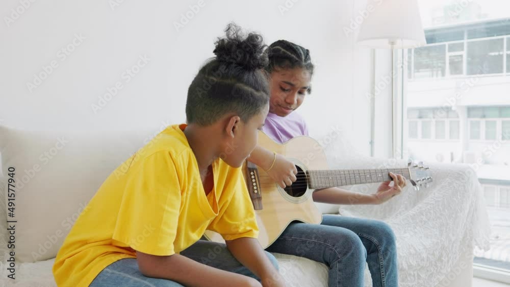 Two African American teenagers learning to play a musical instrument or guitar Two African American teenagers learning to play a musical instrument or guitar