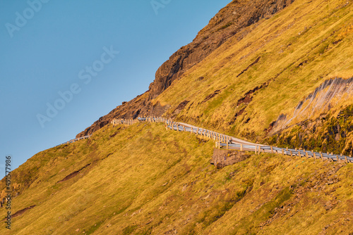 The road is fenced on a steep mountain slope. Tjornuvik, Faroe Islands, Denmark. photo