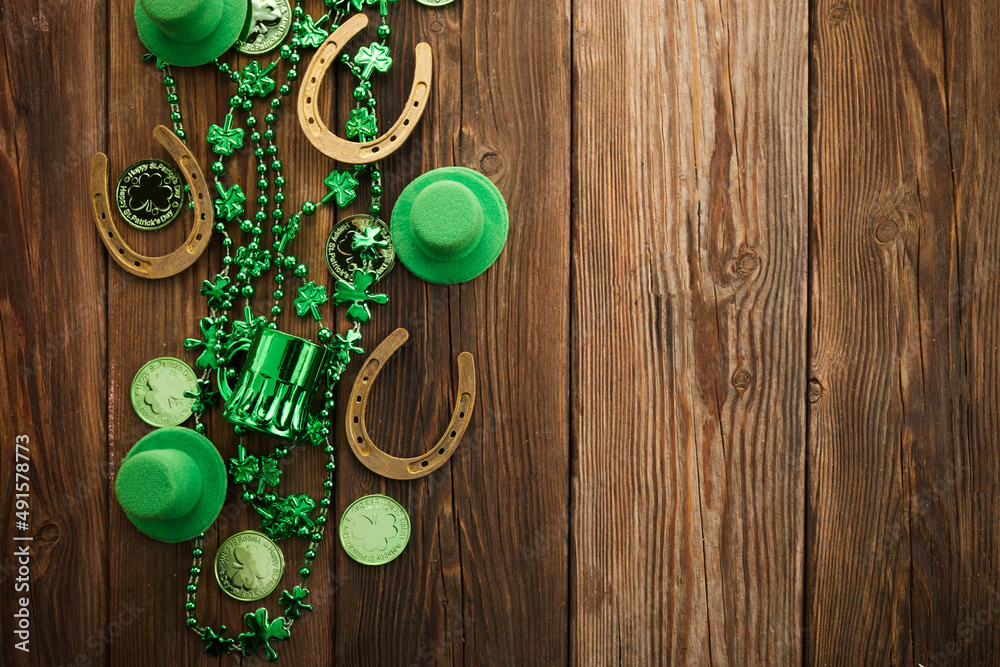 St Patricks Day border of shamrocks beads and coins over a rustic wood background St Patricks Day border of shamrocks beads and coins over a rustic wood background