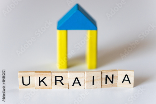 Napis Ukraina, w tle domek z drewnianych klocków w barwach narodowych Ukrainy