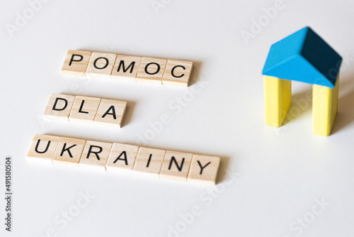 Pomoc wsparcie dla Ukrainy - słowa z literek przy drewnianym domku w barwach narodowych Ukrainy