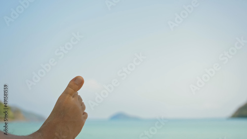 Photography Bare feet of young man removing sand from foot lying on beach near calm azure ocean at exotic resort extreme closeup