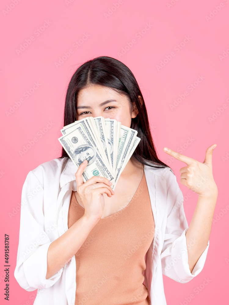 Successful beautiful Asian business young woman holding money US dollar bills in hand on pink background , business concept Successful beautiful Asian business young woman holding money US dollar bills in hand on pink background , business concept