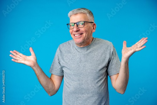 Middle age man over blue background clueless and confused expression with arms raised photo