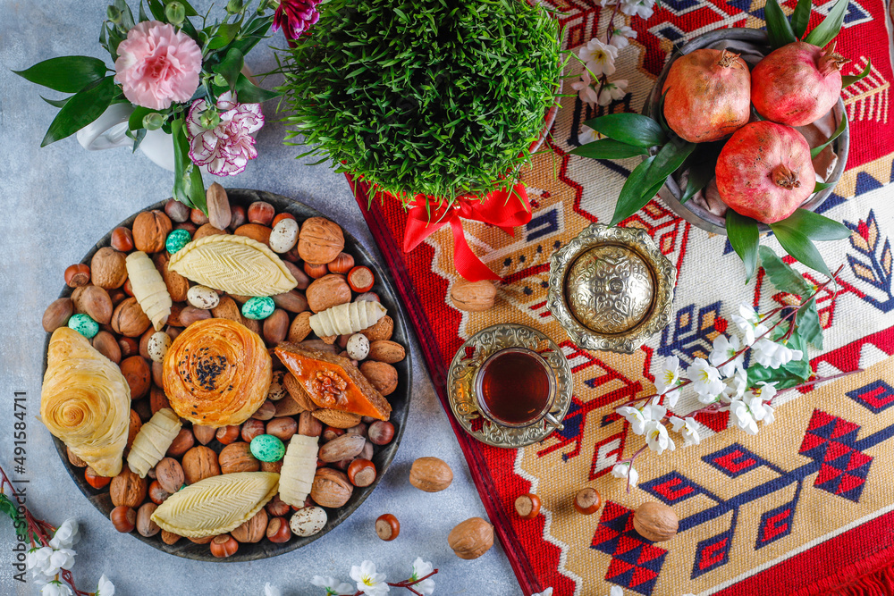 Traditional Azerbaijan spring holiday Novruz tray with semeni - wheat grass, pakhlava, shekerbura,badambura,mutaki,gogal,flowers,dry fruits,spring flowers.