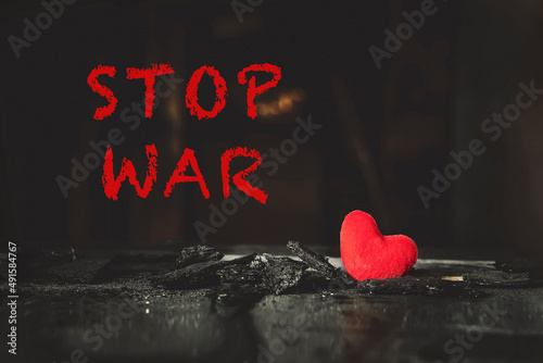 STOP WAR. Red plush heart among the ashes after home fire.