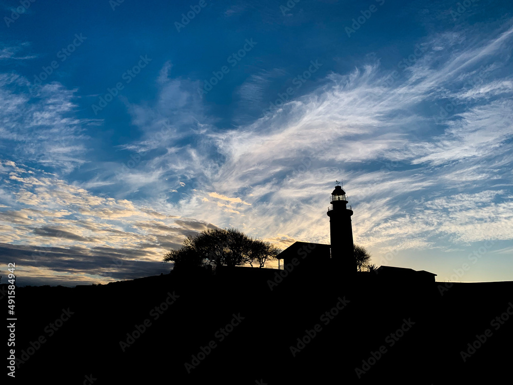 Lighthouse silhouette in the evening landscape Lighthouse silhouette in the evening landscape
