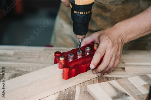 Obraz na płótnie carpenter use drill bit and centering dowel jig or pocket hole jig tool to make strong joints on wooden plate. woodworking concept.selective focus. w salonie