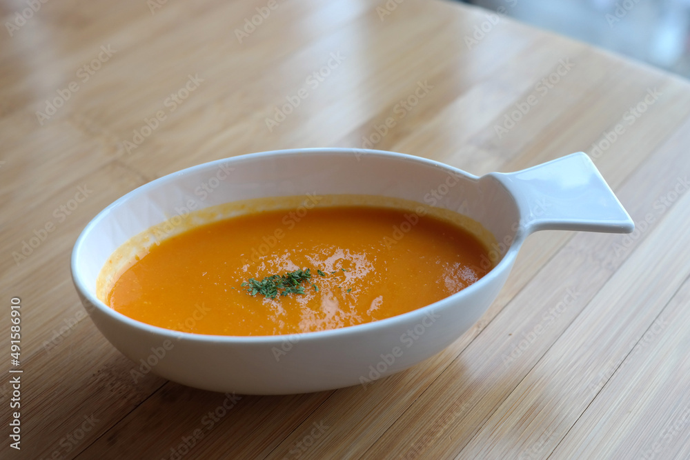 A thick pumpkin soup is served in an oval bowl. A thick pumpkin soup is served in an oval bowl.