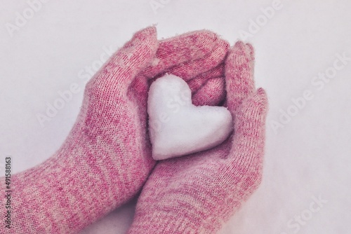 Winter love concept. Heart of snow in the hands of a woman.