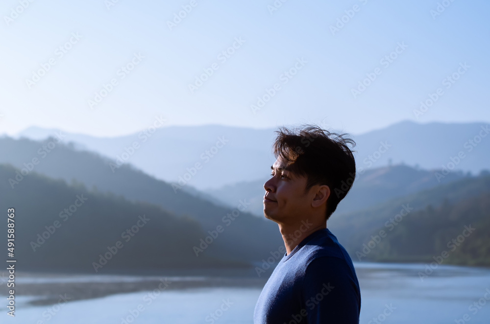 Asian man smiling and looking up with mountain any lake background. Good mental health concept. Asian man smiling and looking up with mountain any lake background. Good mental health concept.