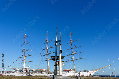 A monument in front of a large sailing ship
