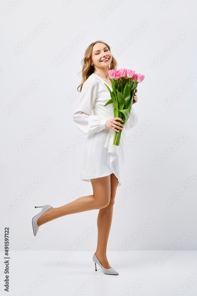 Young woman in white dress hurry with tulips over white background Young woman in white dress hurry with tulips over white background