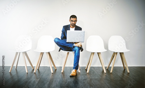 Familiarizing myself with the ins and outs of the company. Shot of a young businessman using a laptop while waiting in line.