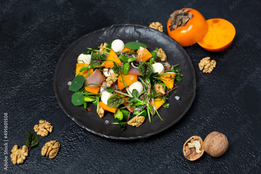 Healthy salad with persimmon, microgreens, nuts and feta cheese. Fitness nutrition